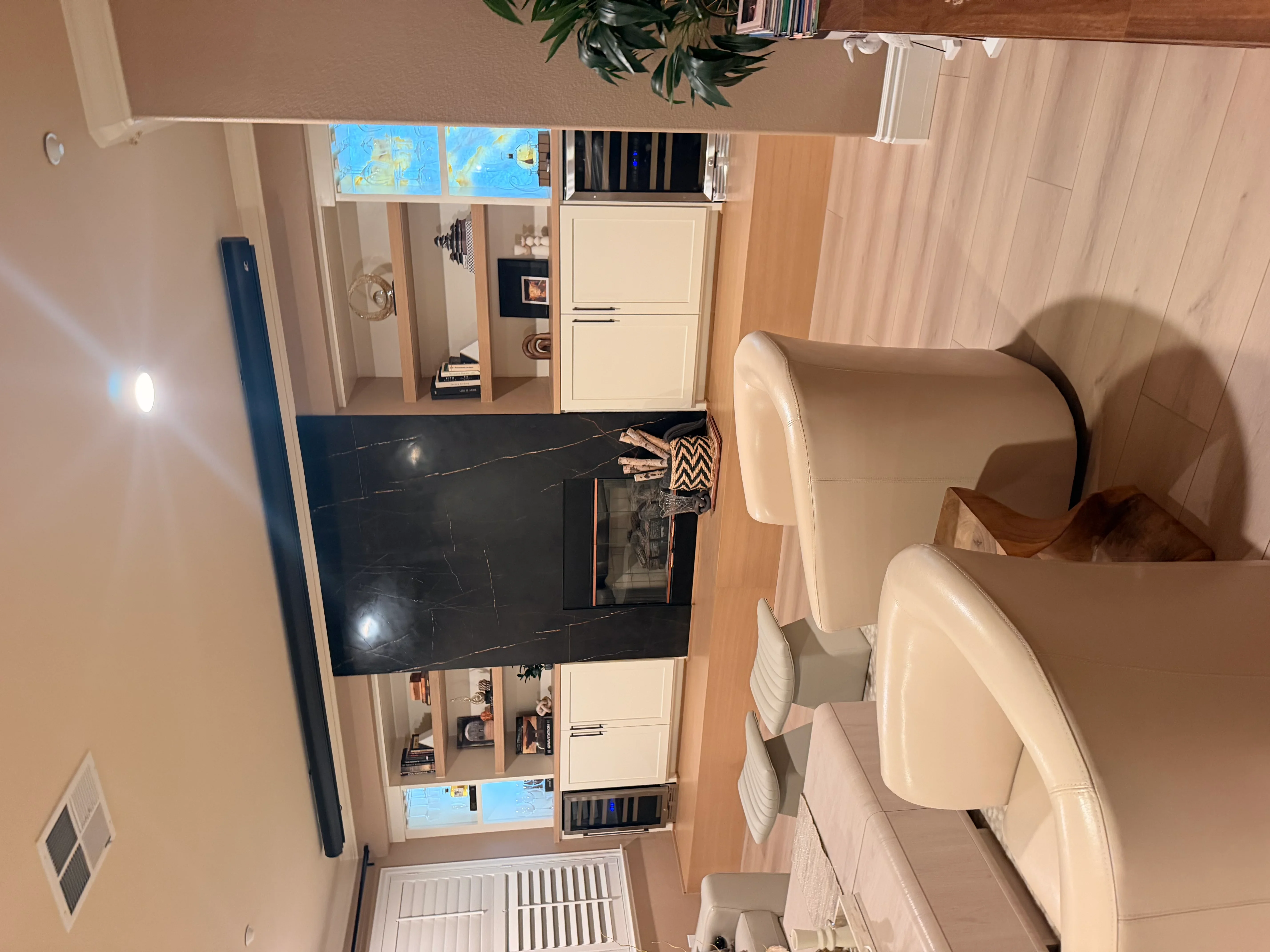 Custom built-in shelving with cream cabinets, glass doors, and black accent panel in living room