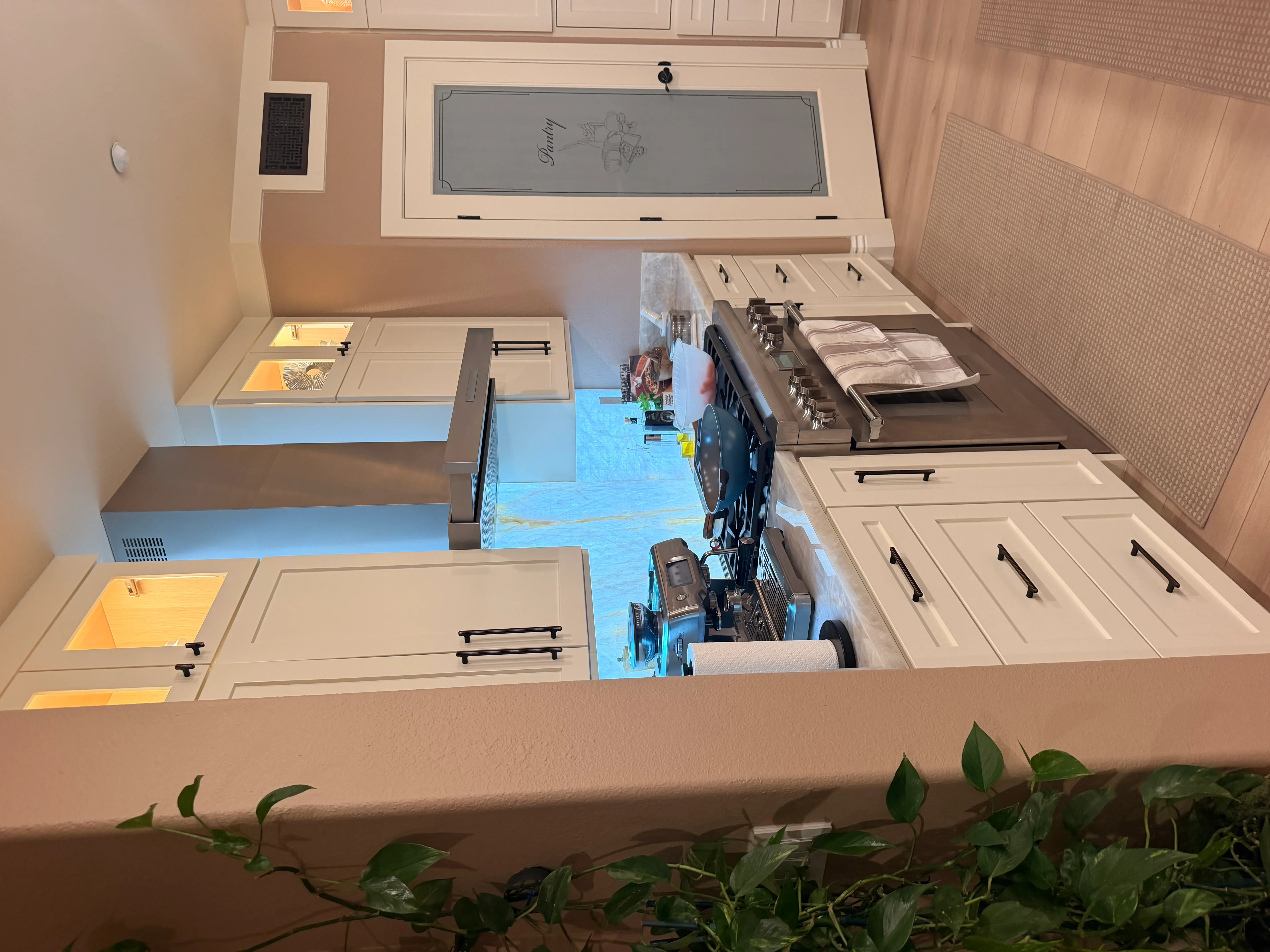 Cream kitchen cabinets with black handles, blue epoxy countertops, and tile backsplash installation