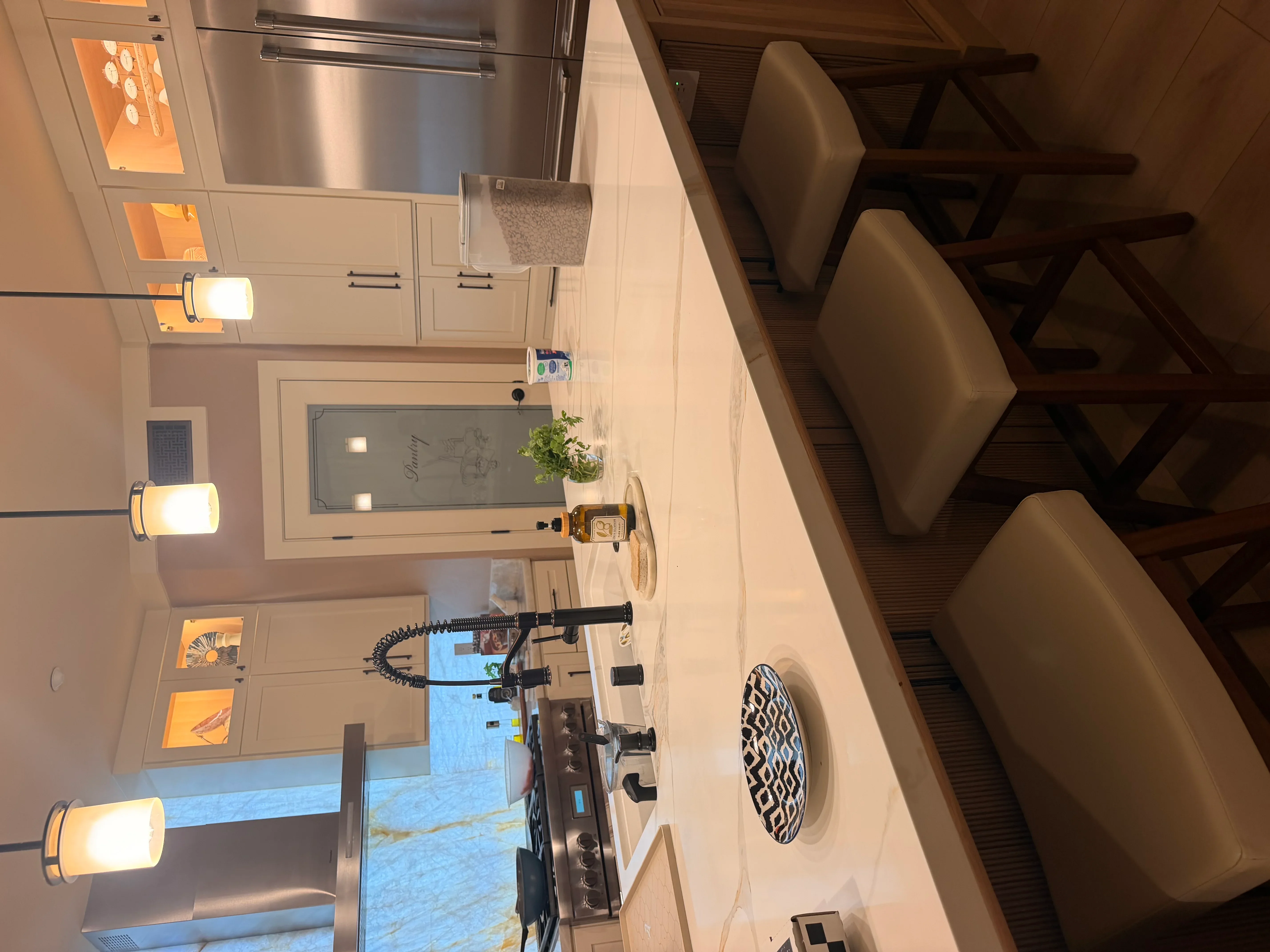 Kitchen with cream cabinetry, stainless steel refrigerator, marble counters, and pendant lighting